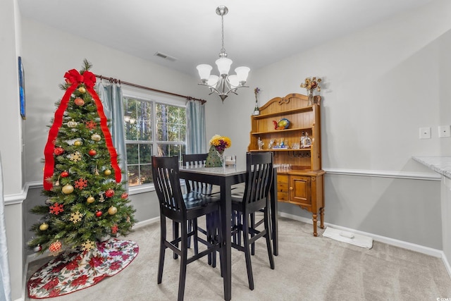 carpeted dining area with an inviting chandelier