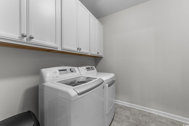 clothes washing area with cabinets and separate washer and dryer