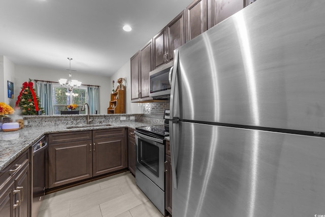 kitchen featuring light stone countertops, sink, kitchen peninsula, a chandelier, and appliances with stainless steel finishes