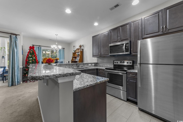 kitchen with kitchen peninsula, a wealth of natural light, hanging light fixtures, and stainless steel appliances