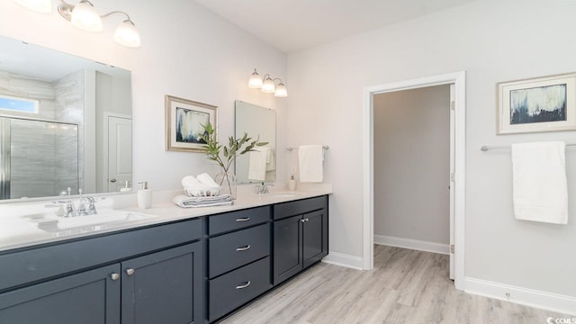 bathroom with hardwood / wood-style flooring, vanity, and a shower with door