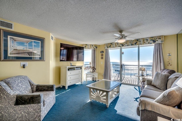 living room featuring carpet, ceiling fan, and a textured ceiling