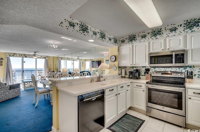 kitchen featuring kitchen peninsula, a textured ceiling, stainless steel appliances, and white cabinets