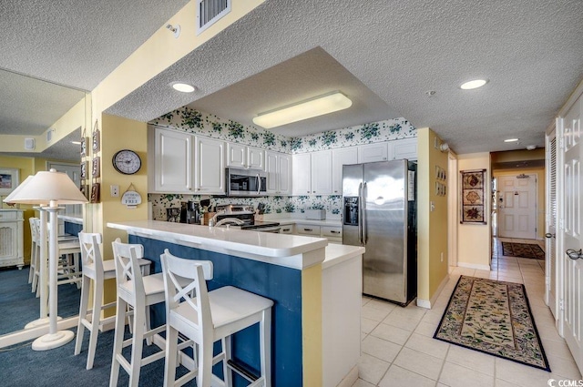 kitchen with kitchen peninsula, white cabinets, stainless steel appliances, and a textured ceiling