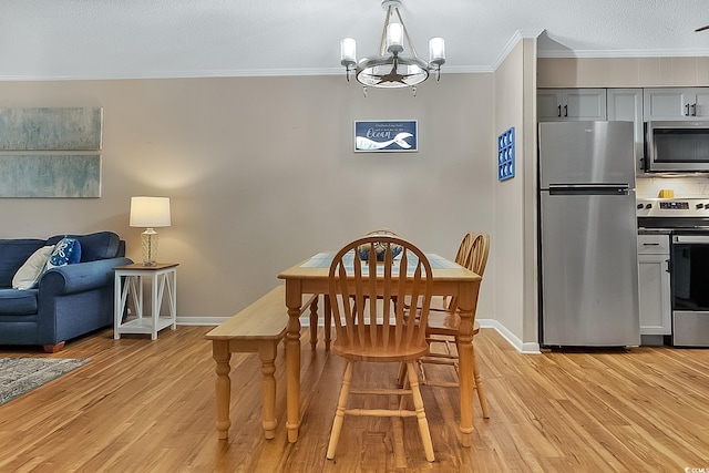 dining space featuring a textured ceiling, light wood-type flooring, an inviting chandelier, and ornamental molding