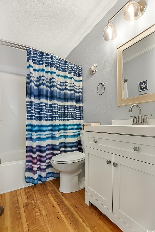 full bathroom featuring shower / bath combo, vanity, hardwood / wood-style flooring, toilet, and a textured ceiling