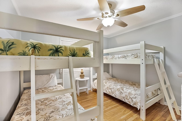 bedroom with wood-type flooring, a textured ceiling, ceiling fan, and ornamental molding