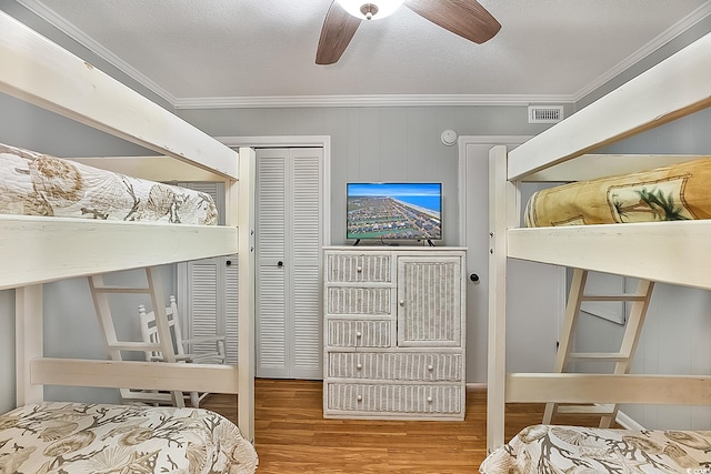 bedroom featuring ceiling fan, wood-type flooring, a textured ceiling, and ornamental molding