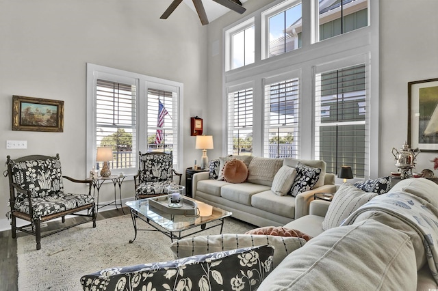living room featuring baseboards, wood finished floors, a high ceiling, and ceiling fan