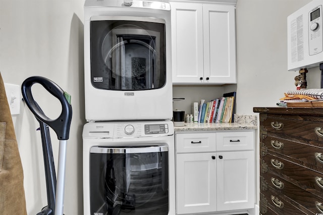 washroom featuring stacked washer / drying machine and cabinet space