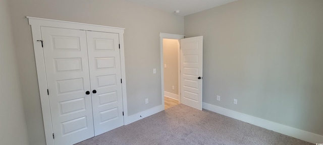 unfurnished bedroom featuring light carpet and a closet