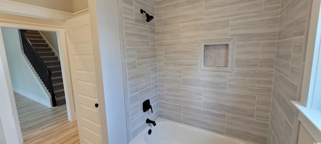 bathroom with hardwood / wood-style floors and tiled shower / bath