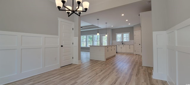 kitchen featuring an inviting chandelier, white cabinets, light hardwood / wood-style floors, decorative light fixtures, and a kitchen island