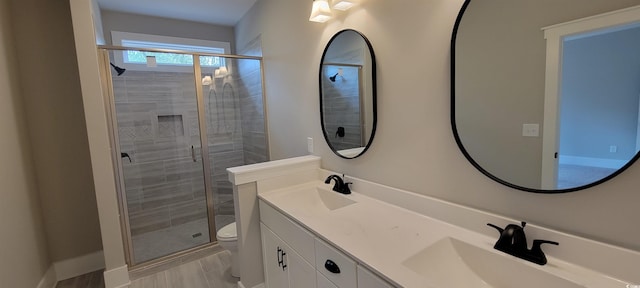 bathroom featuring vanity, toilet, and a shower with shower door