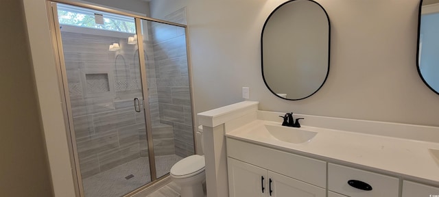 bathroom featuring vanity, toilet, and a shower with shower door