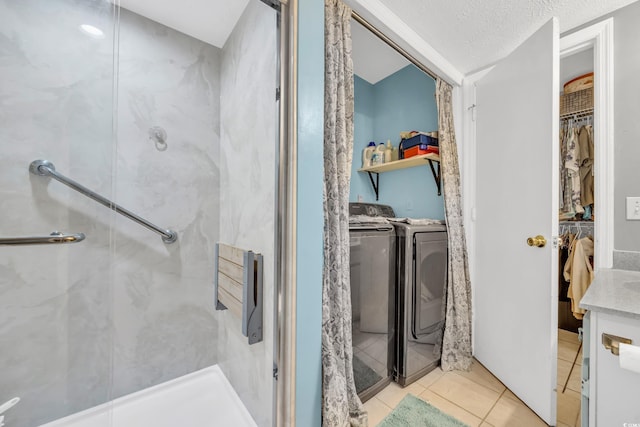 bathroom featuring tile patterned floors, a textured ceiling, washer and clothes dryer, vanity, and a shower with shower door