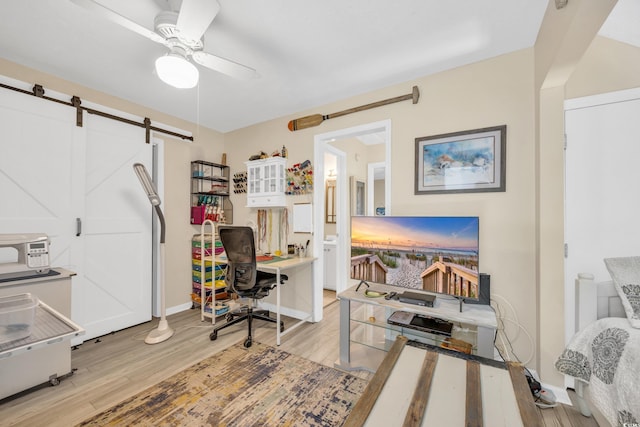 office space featuring a barn door, light hardwood / wood-style floors, and ceiling fan