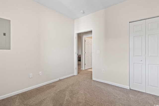 unfurnished bedroom featuring electric panel, light colored carpet, and a closet