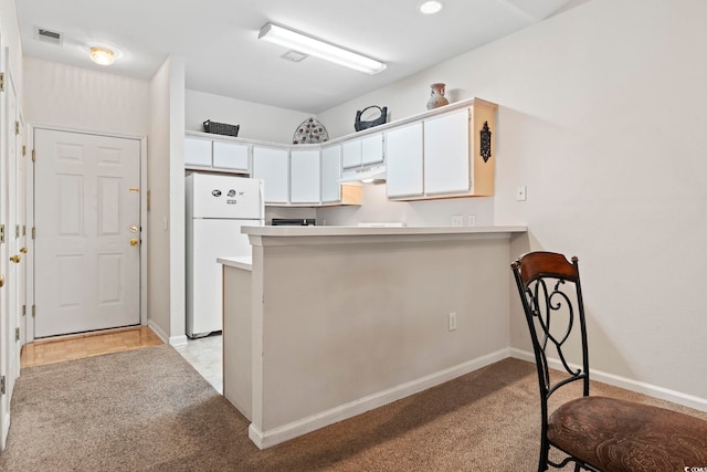 kitchen featuring kitchen peninsula, light carpet, white refrigerator, and white cabinetry