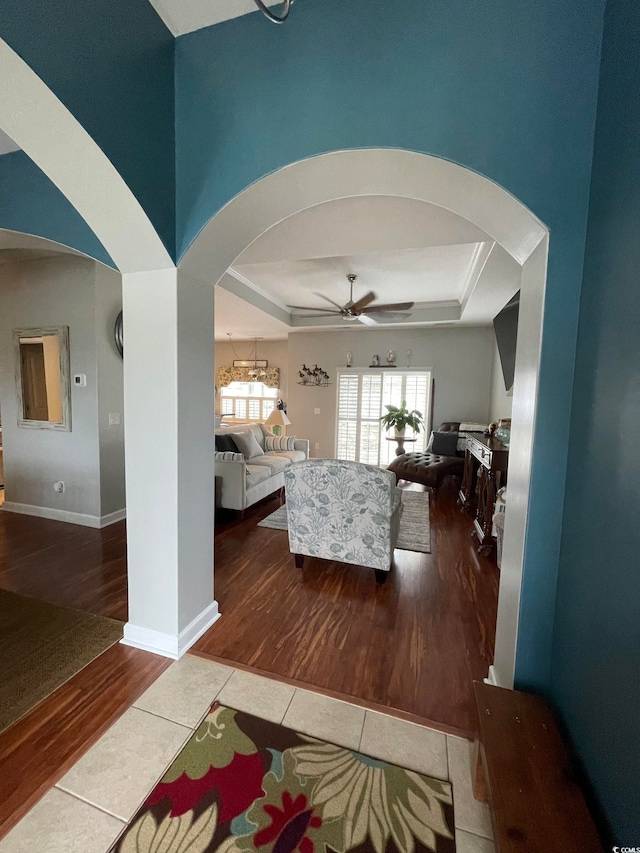 interior space with tile patterned flooring, a tray ceiling, and ceiling fan