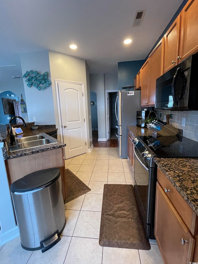 kitchen with backsplash, sink, light tile patterned floors, and stainless steel appliances