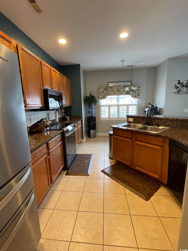 kitchen with sink, tasteful backsplash, pendant lighting, light tile patterned flooring, and black appliances