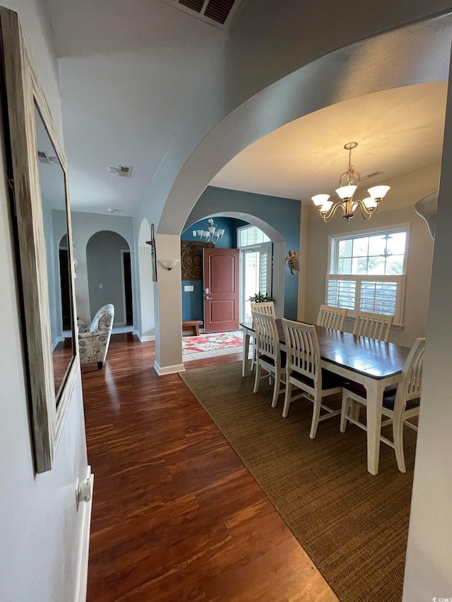 dining room with dark hardwood / wood-style flooring, an inviting chandelier, and a wealth of natural light