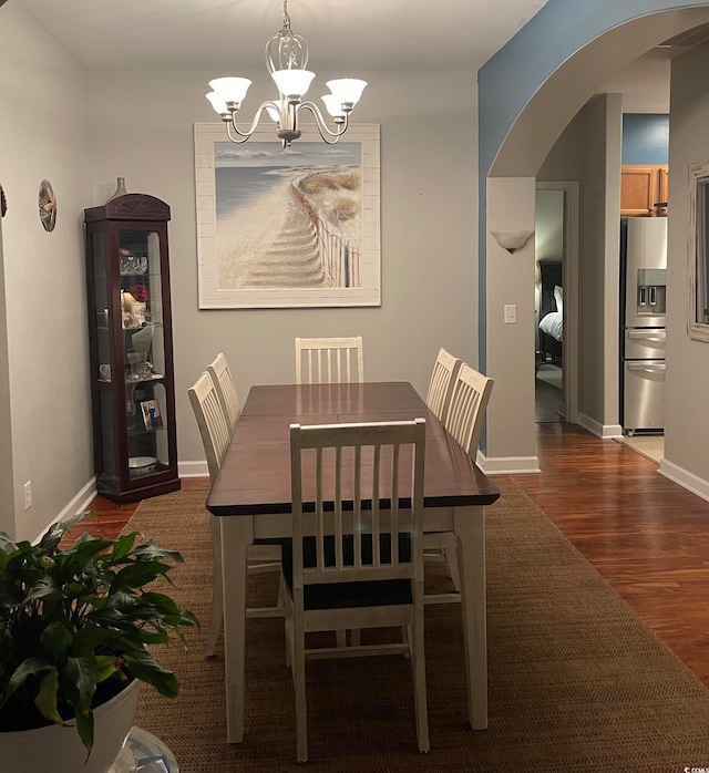 dining room with dark hardwood / wood-style flooring and an inviting chandelier