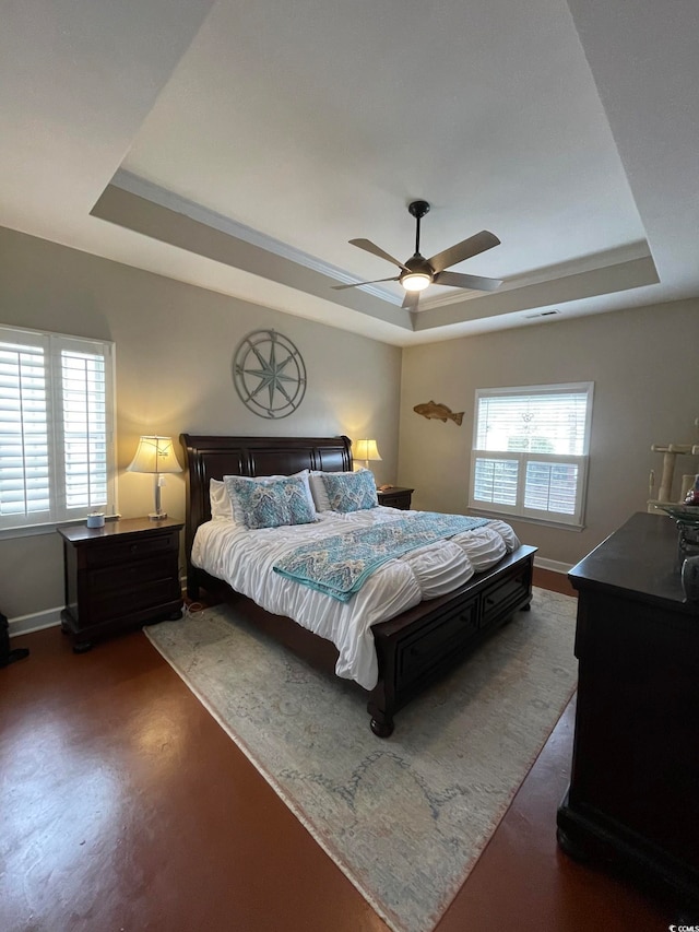 bedroom with multiple windows, a tray ceiling, and ceiling fan