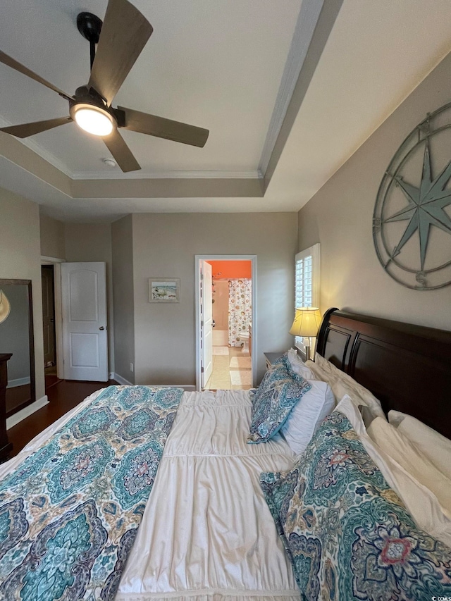 bedroom with a tray ceiling, ceiling fan, crown molding, and ensuite bathroom