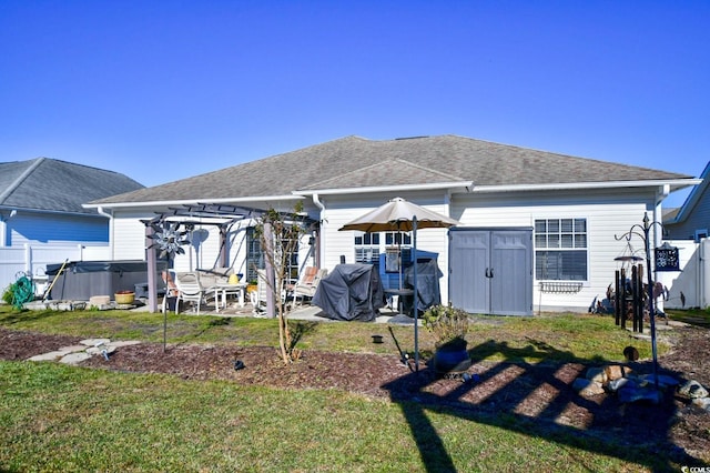 rear view of property featuring a patio area, a pergola, a yard, and a hot tub