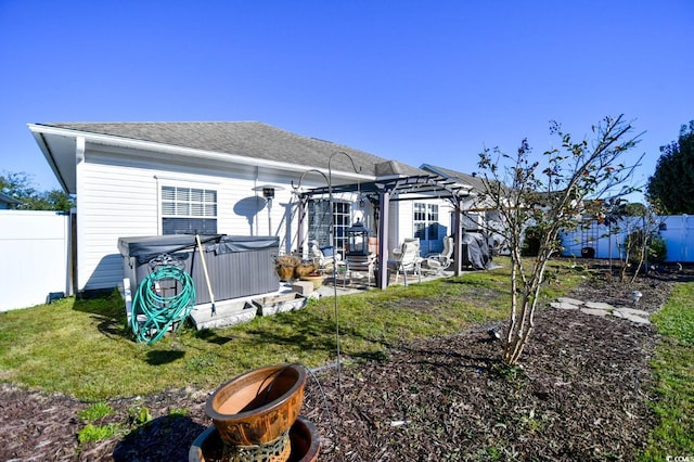 back of house featuring a yard, a pergola, a hot tub, and a patio