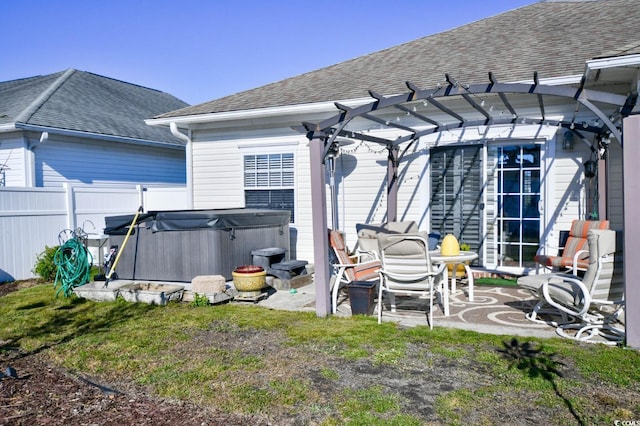 rear view of property featuring a pergola, a hot tub, and a patio area