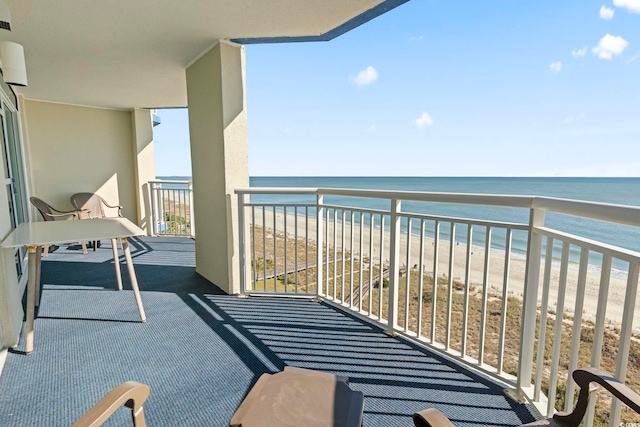 balcony with a water view and a view of the beach