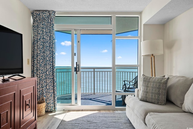 living room with hardwood / wood-style flooring, a water view, and a textured ceiling