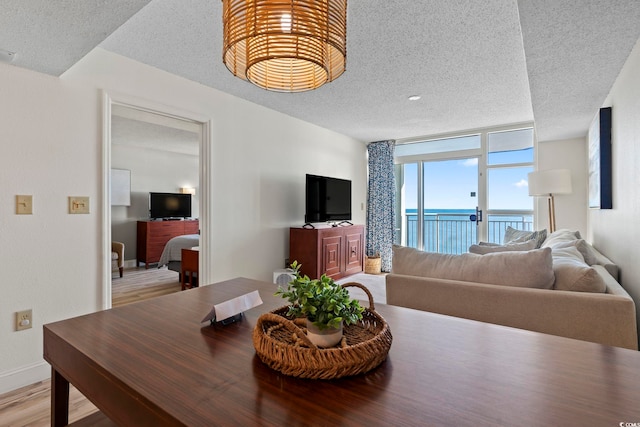 dining area featuring expansive windows, a textured ceiling, and light wood-type flooring