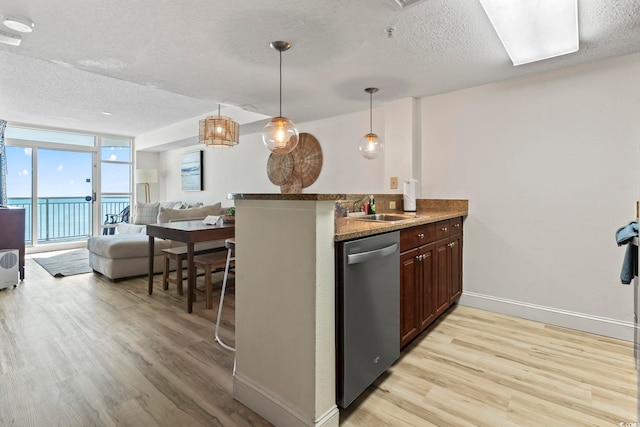 kitchen with a kitchen bar, light wood-type flooring, stainless steel dishwasher, and sink