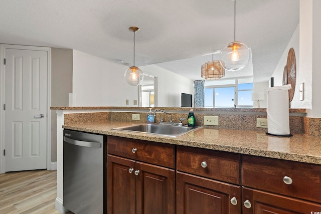 kitchen featuring stainless steel dishwasher, sink, hanging light fixtures, and light hardwood / wood-style flooring