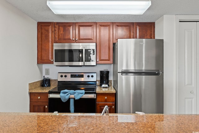 kitchen with a textured ceiling, sink, and stainless steel appliances