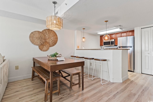 dining room featuring light hardwood / wood-style floors and a textured ceiling