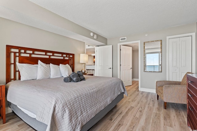 bedroom featuring a closet, a textured ceiling, and light wood-type flooring