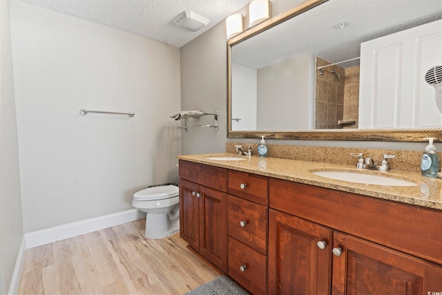 bathroom featuring vanity, toilet, wood-type flooring, and a textured ceiling