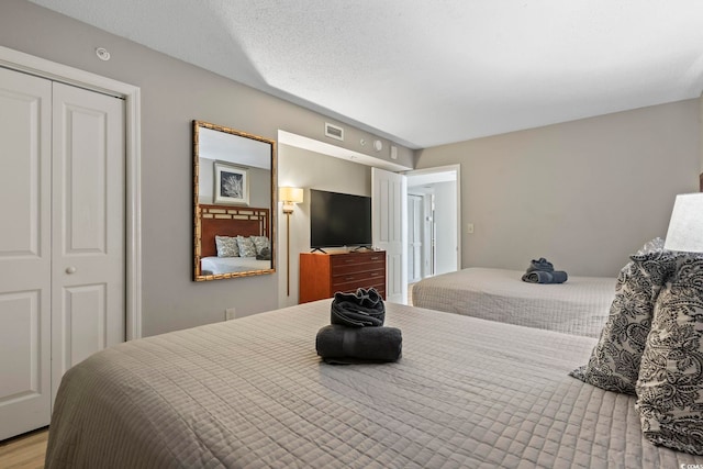 bedroom featuring light wood-type flooring, a textured ceiling, and a closet