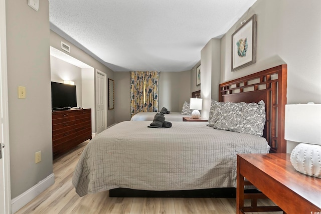 bedroom with a textured ceiling and light hardwood / wood-style floors