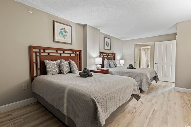 bedroom with light wood-type flooring and a textured ceiling