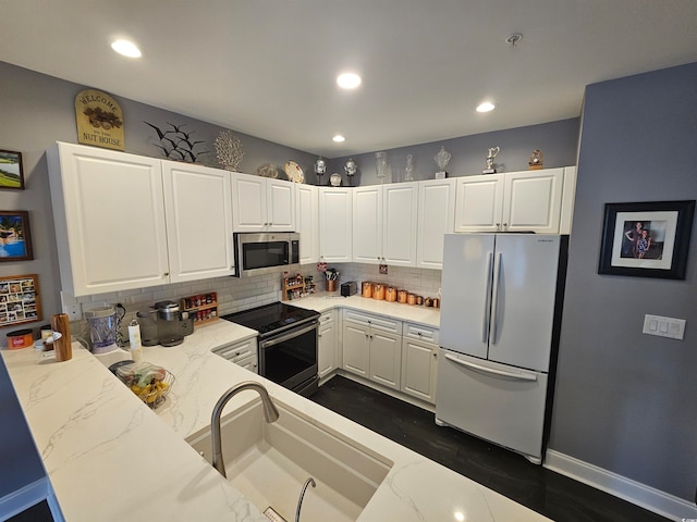 kitchen with white cabinets, kitchen peninsula, stainless steel appliances, and tasteful backsplash