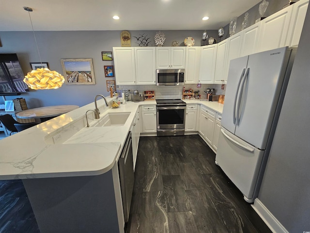 kitchen with kitchen peninsula, stainless steel appliances, sink, pendant lighting, and white cabinets