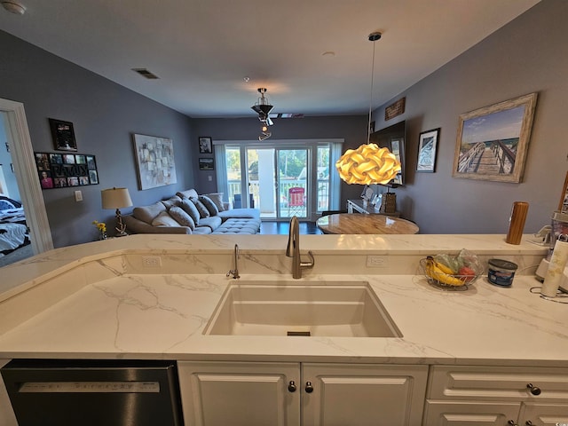 kitchen featuring light stone countertops, white cabinets, sink, dishwasher, and hanging light fixtures