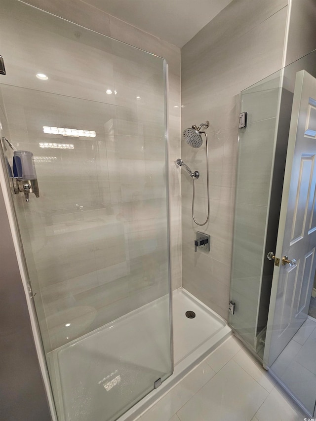 bathroom with a shower with door and tile patterned flooring