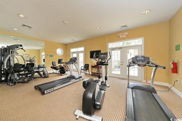 exercise room featuring light carpet and french doors